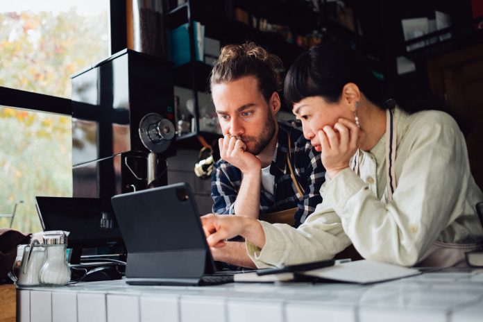 Two Colleagues Using A Digital Tablet While Working Together In A Coffee Shop